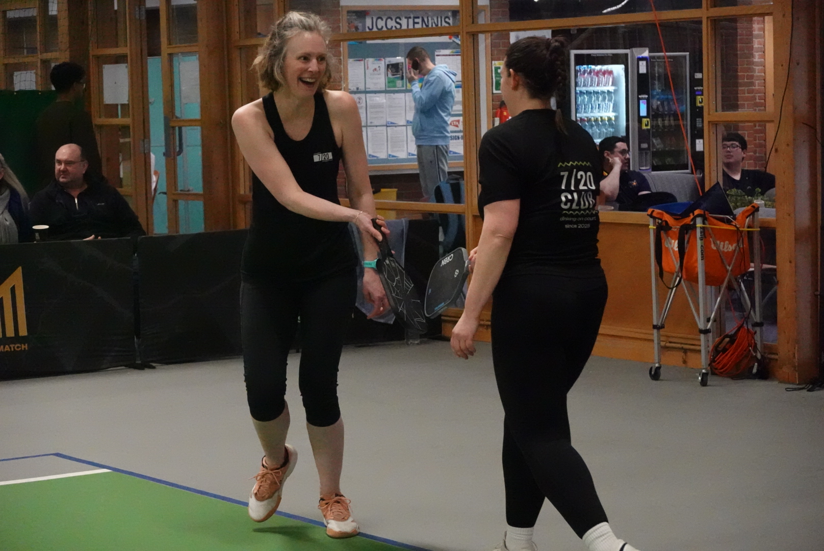 A doubles player reaching forward to attack a ball at the kitchen line.