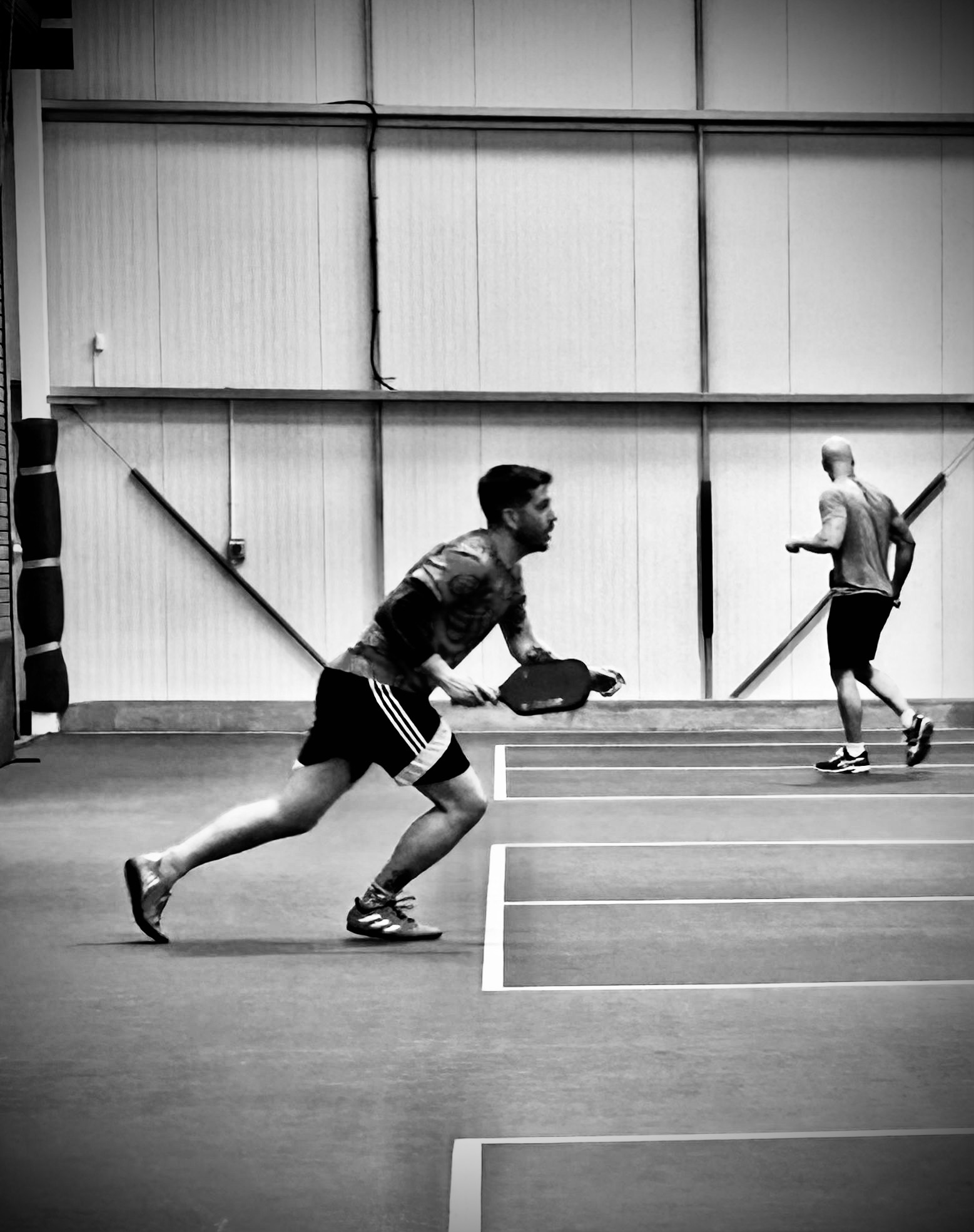 Black and white photo of two players resetting between rallies on an indoor court.
