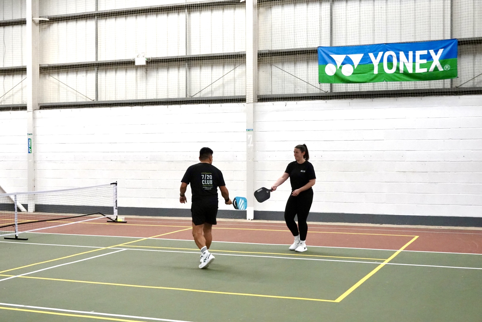 Two players in black club shirts warming up side by side on court.