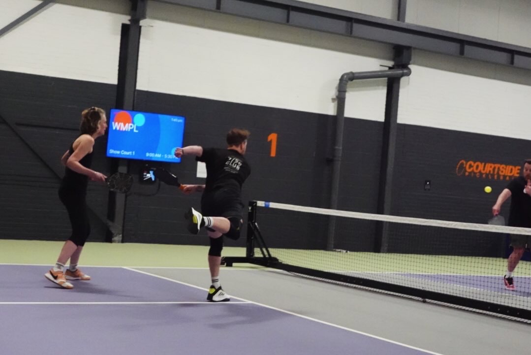 Two club members dressed as Mario and Luigi posing with paddles beside the club banner.